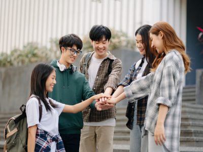 Asian Students are studying the campus park. Young people are spending time together. Reading book, working with laptop, tablet and communicating while sitting on stairs